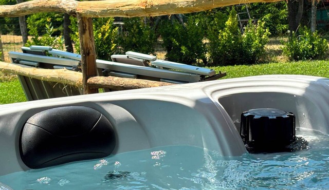Room with a kitchenette and a hot tub on the veranda; garden with lounge chairs